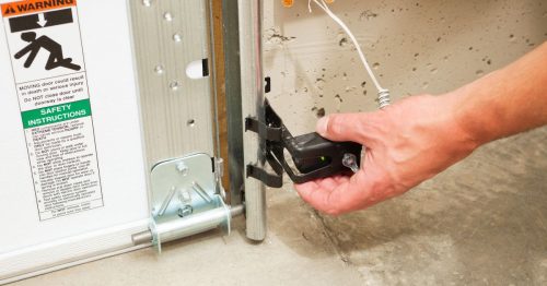 Hand adjusting a garage door reversing sensor