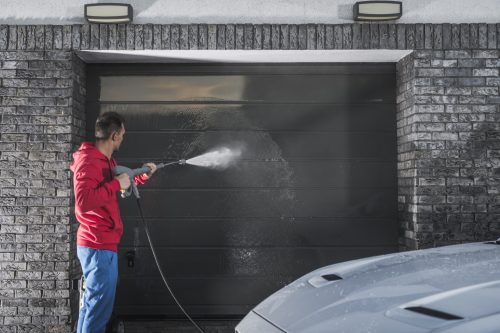 A man performs garage door maintenance and cleaning to his garage door