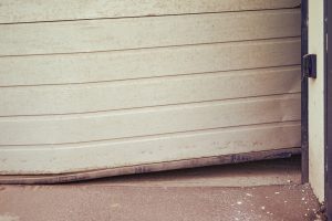 A garage door off track and hanging sideways