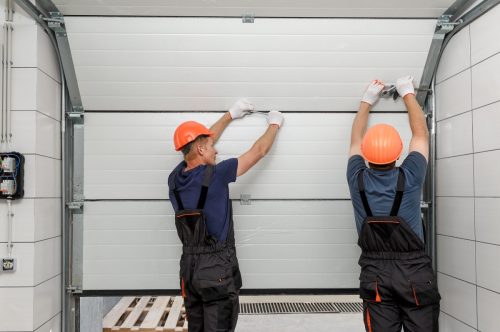 Workers performing garage door panel replacement for a customer
