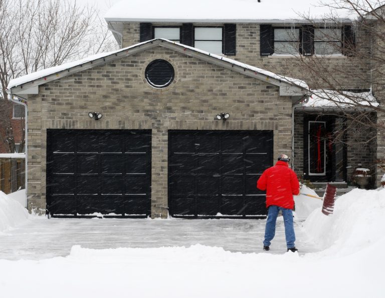 A man shovels snow as he winterizes his garage